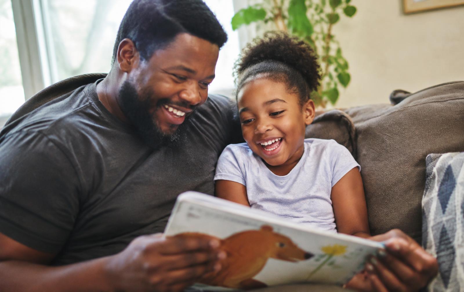Dad and daughter laughing over a picture book